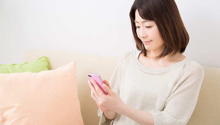 女性がスマートフォンで一括査定サイトを利用している様子